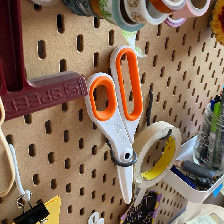 Slice<sup>®</sup> 10545 Large Ceramic Scissors hang on a pegboard in a workshop.