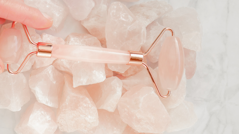 rose quartz roller with raw rose quartz and hand