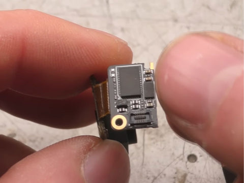 A man with a very small circuit board is looking at its problems