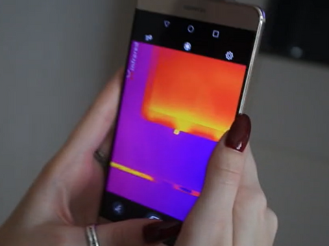 03 A woman using a smartphone thermal imager to inspect the room for hidden devices