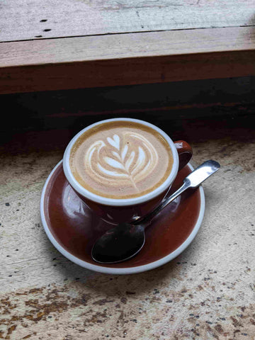 cup of coffee in a brown cup with brown saucer and silver teaspoon