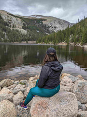 Woman in RECOSIVITY leggings sitting on a rock by a lake