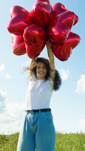 Women holding bunch of heart balloons above her head