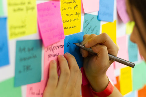 Woman writing on colored sticky notes stuck on wall