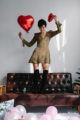 Woman dancing on her sofa holding heart balloons