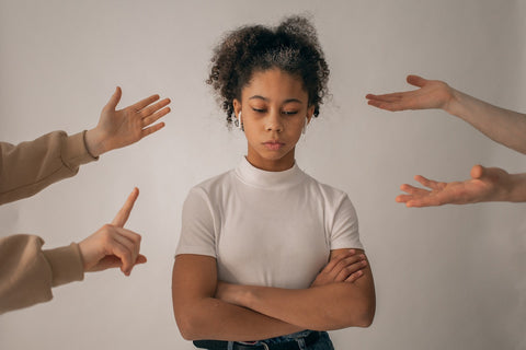 A sad looking woman with other people's arms stretching out around her