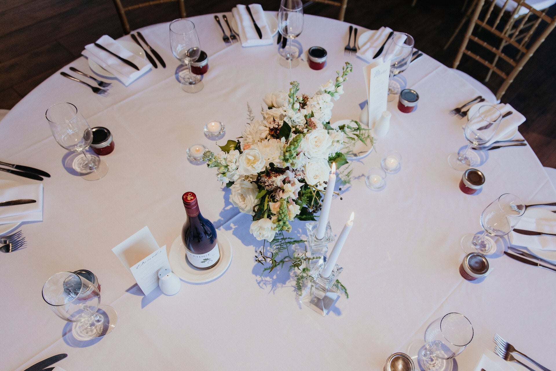 Guest table floral decor, flower filled compote bowls with tall dinner candles.