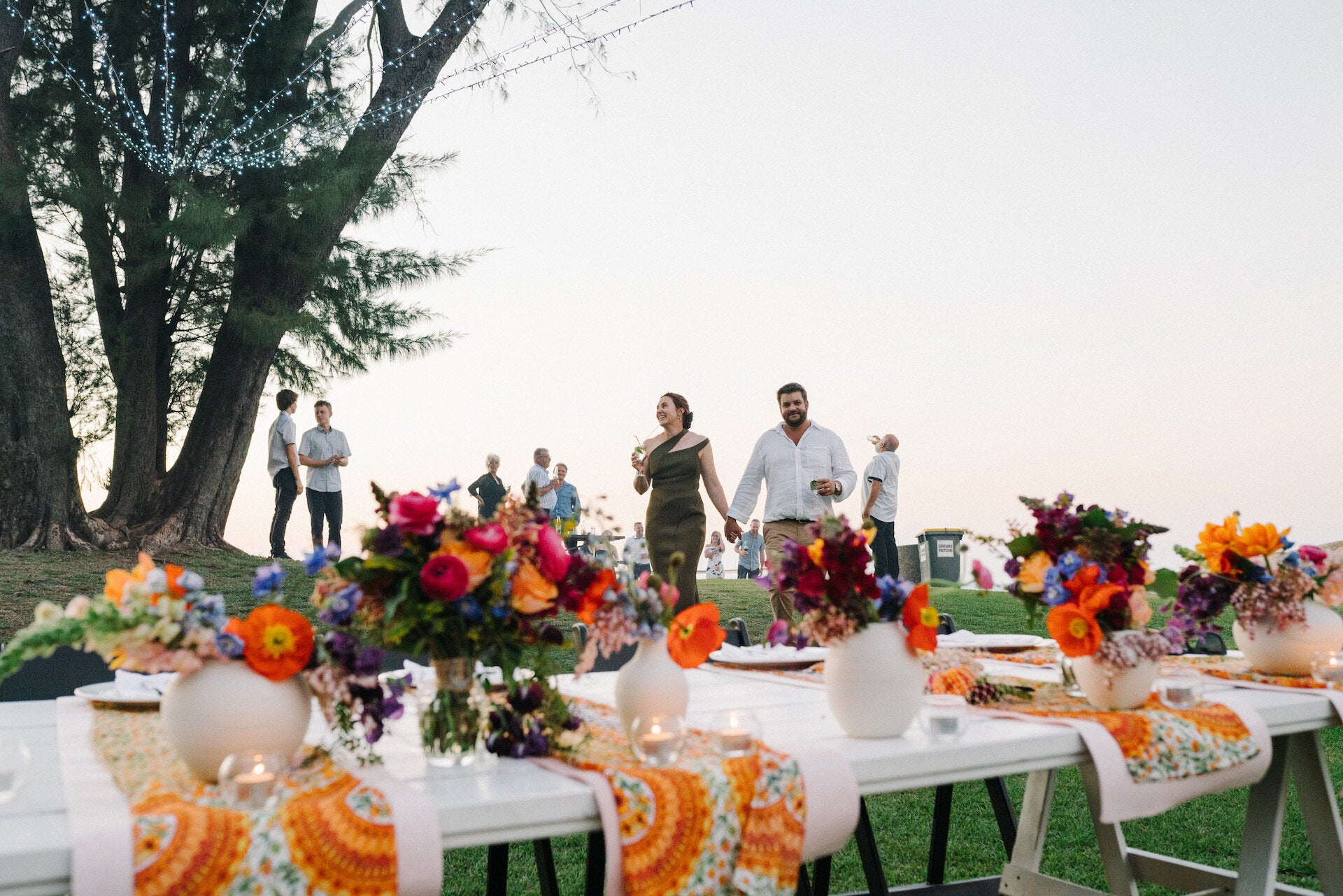 Wedding reception table decor, porcelain vases topped with bright coloured flowers to match table runners. 