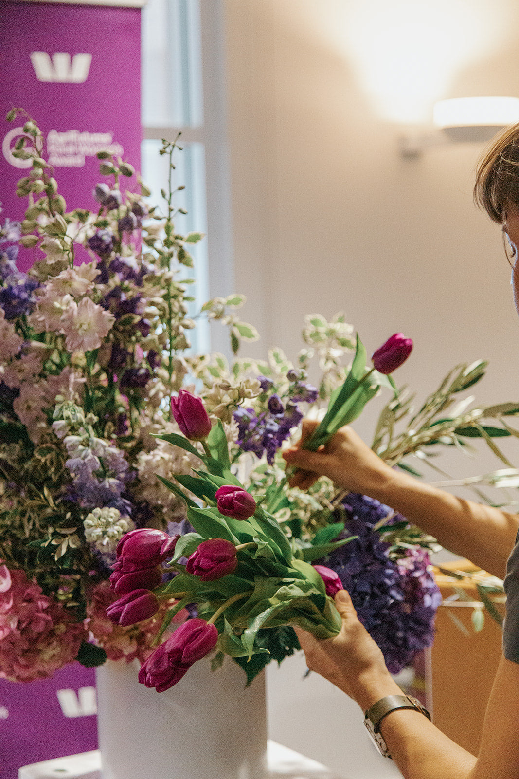 Maria arranging flowers in a vase on a table