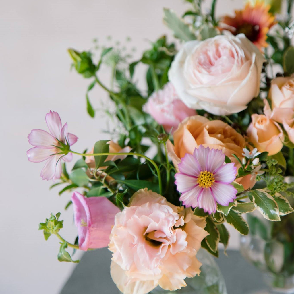 a vase of Pantone-Peachy themed flowers on a concrete plinth