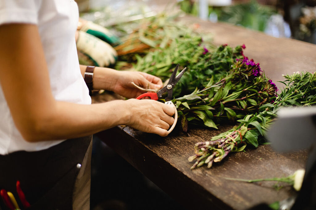 a beija flor florist cutting up flowers on a wooden table