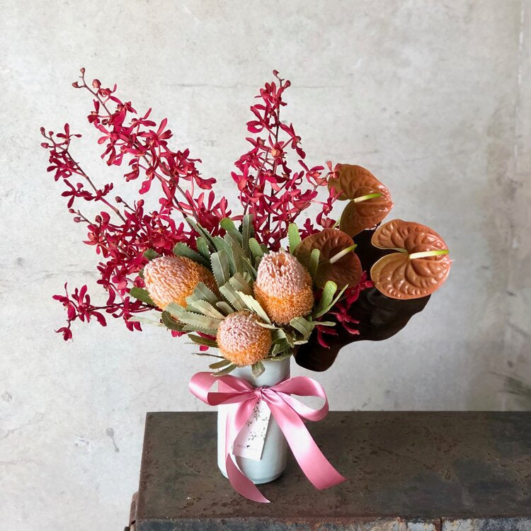 a beija flor vase filled with red flowers on top of a table