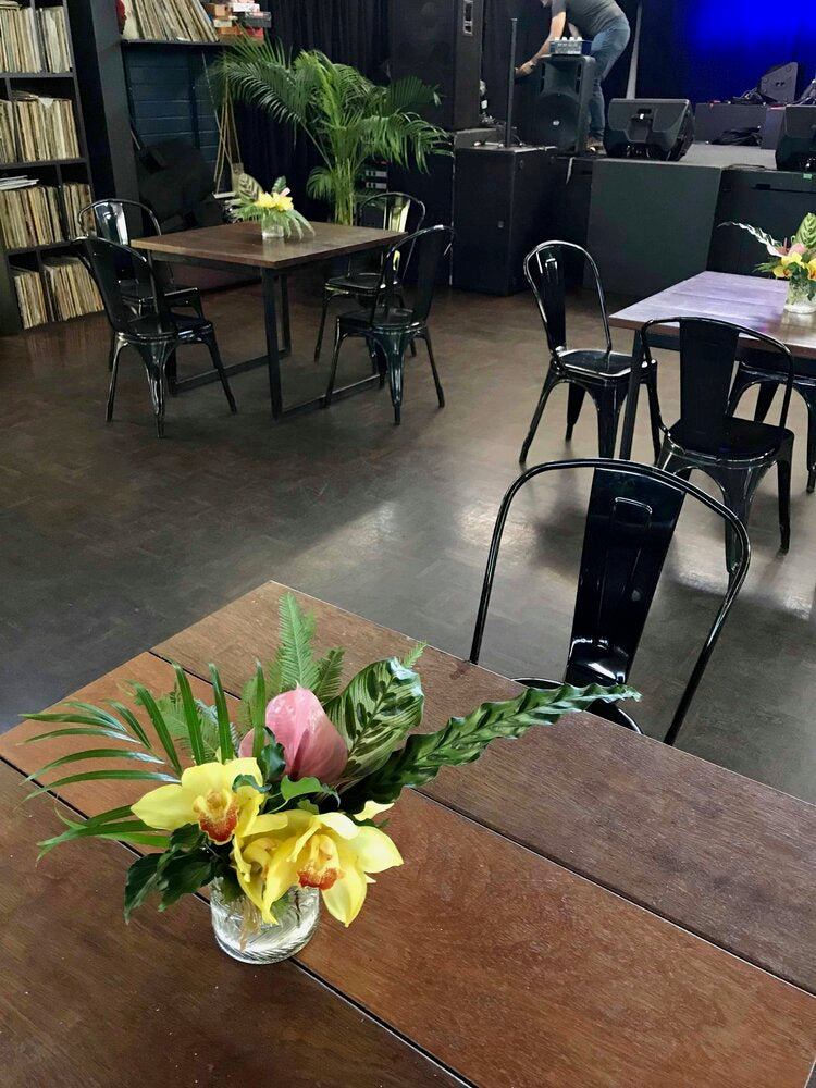 a mini vase floral arrangement sitting on top of a wooden table