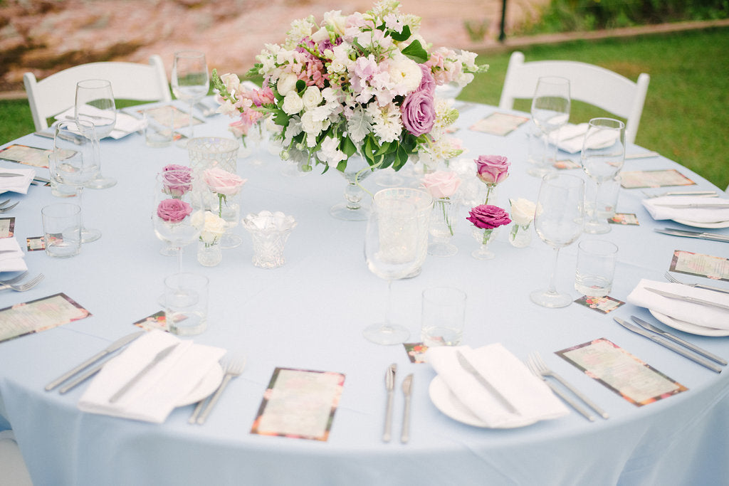 a table set with place settings and flower arrangement from beija flor