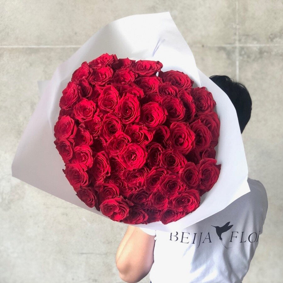 beija flor florist holding a huge bouquet of red roses