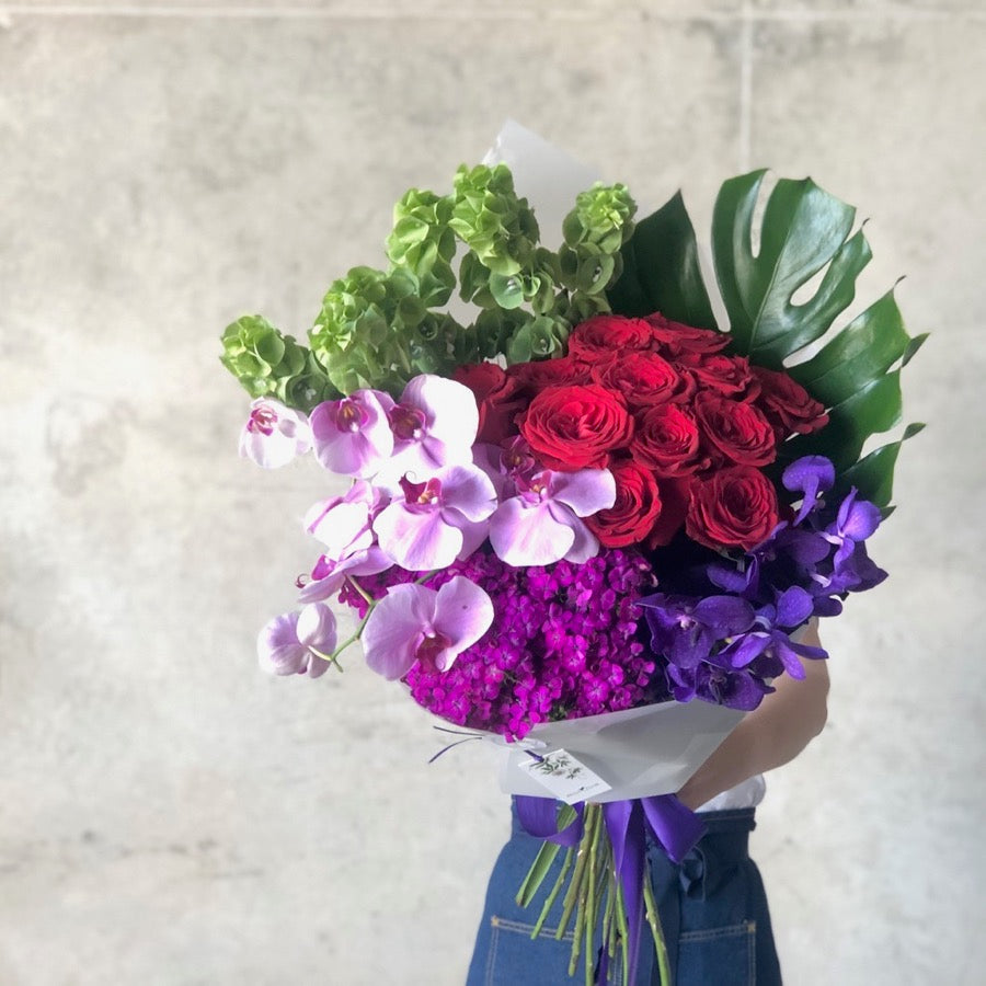 florist holding a bouquet of colorful flowers in pinks, purlple, red and green