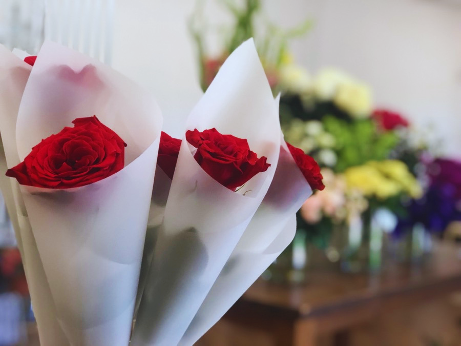 a bunch of wrapped red roses and flowers that are sitting on a table