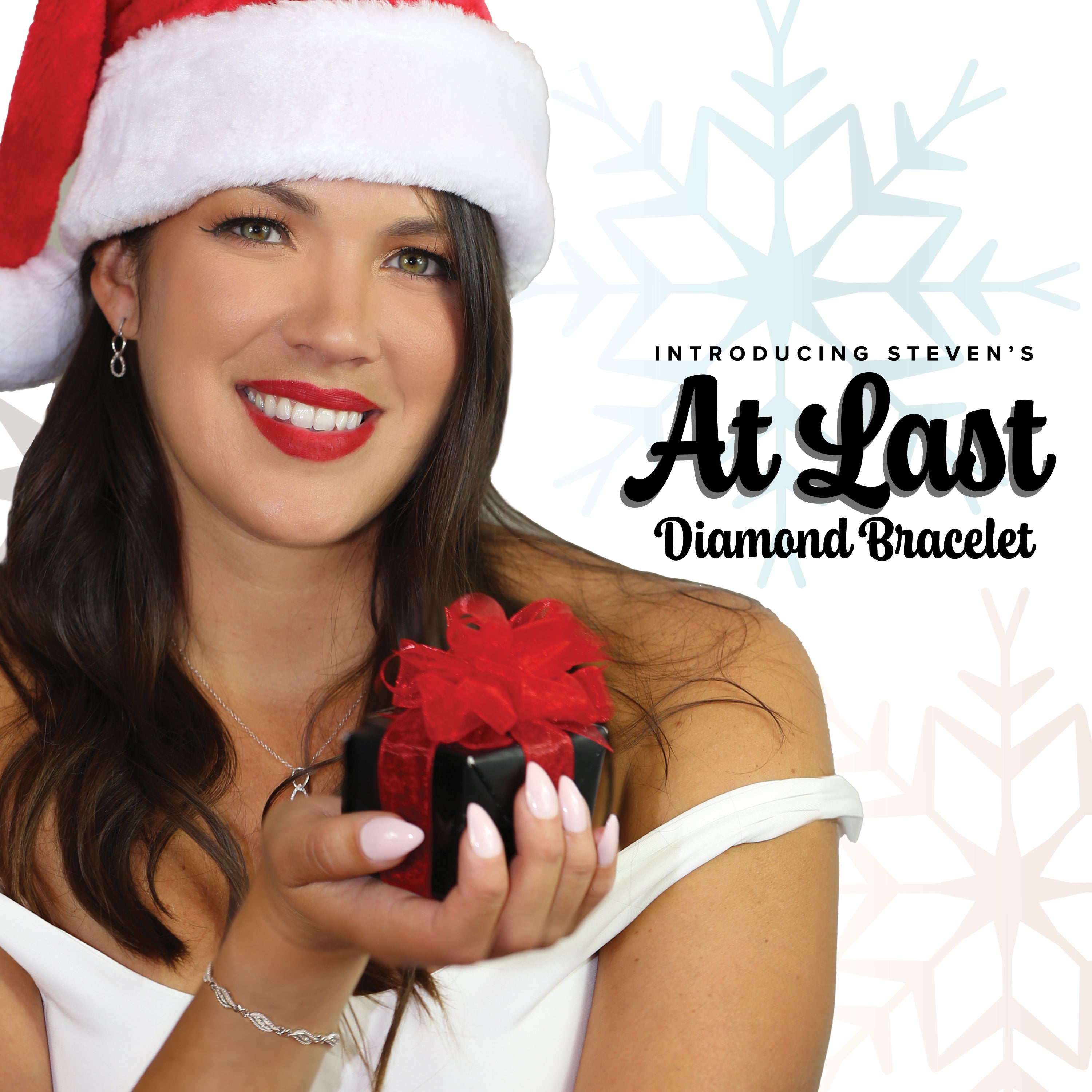 Introducing Steven's At Last Diamond Bracelet. A woman wearing a Santa hat is holding a gift while wearing the At Last Diamond Bracelet