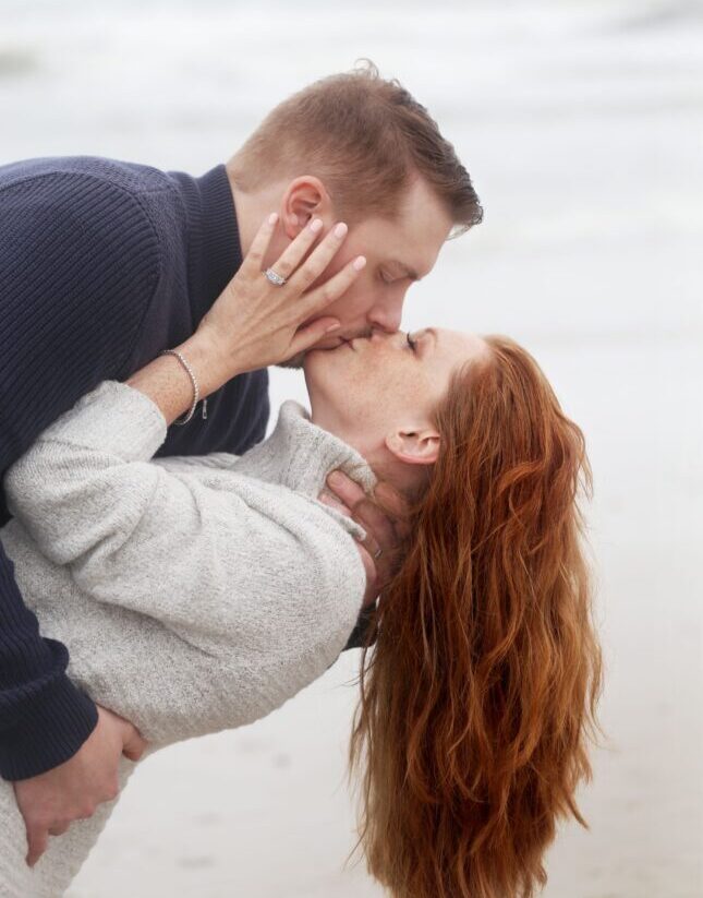 Couple kissing on the beach showing hand with jewelry