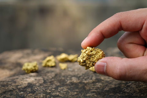 A hand holding a piece of raw gold