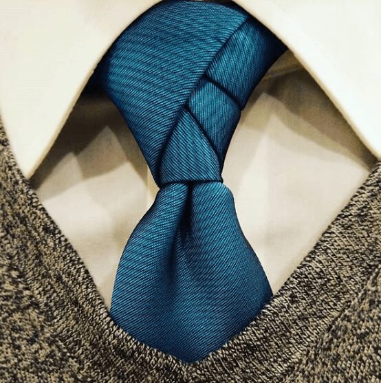 A close up on a white collared shirt with a blue tie.