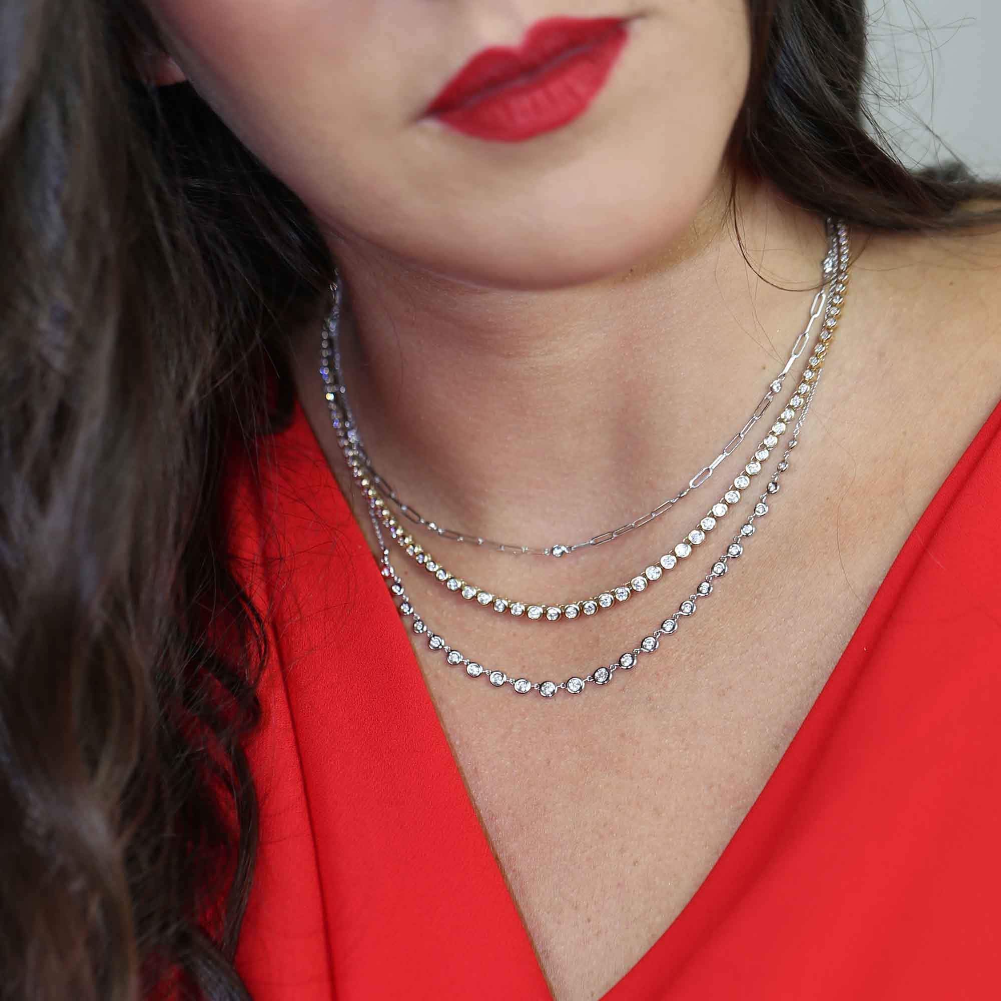 Women in red wearing layered diamond tennis necklaces