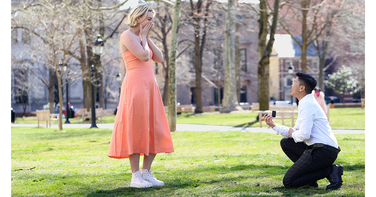 A woman in a pink dress in disbelief of her significant other's proposal. 