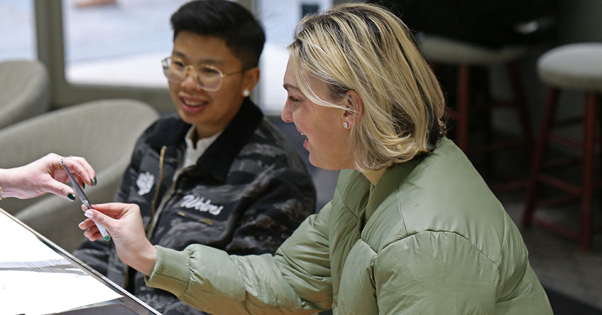 Two young lady's at our store looking at a diamond with tweezers.