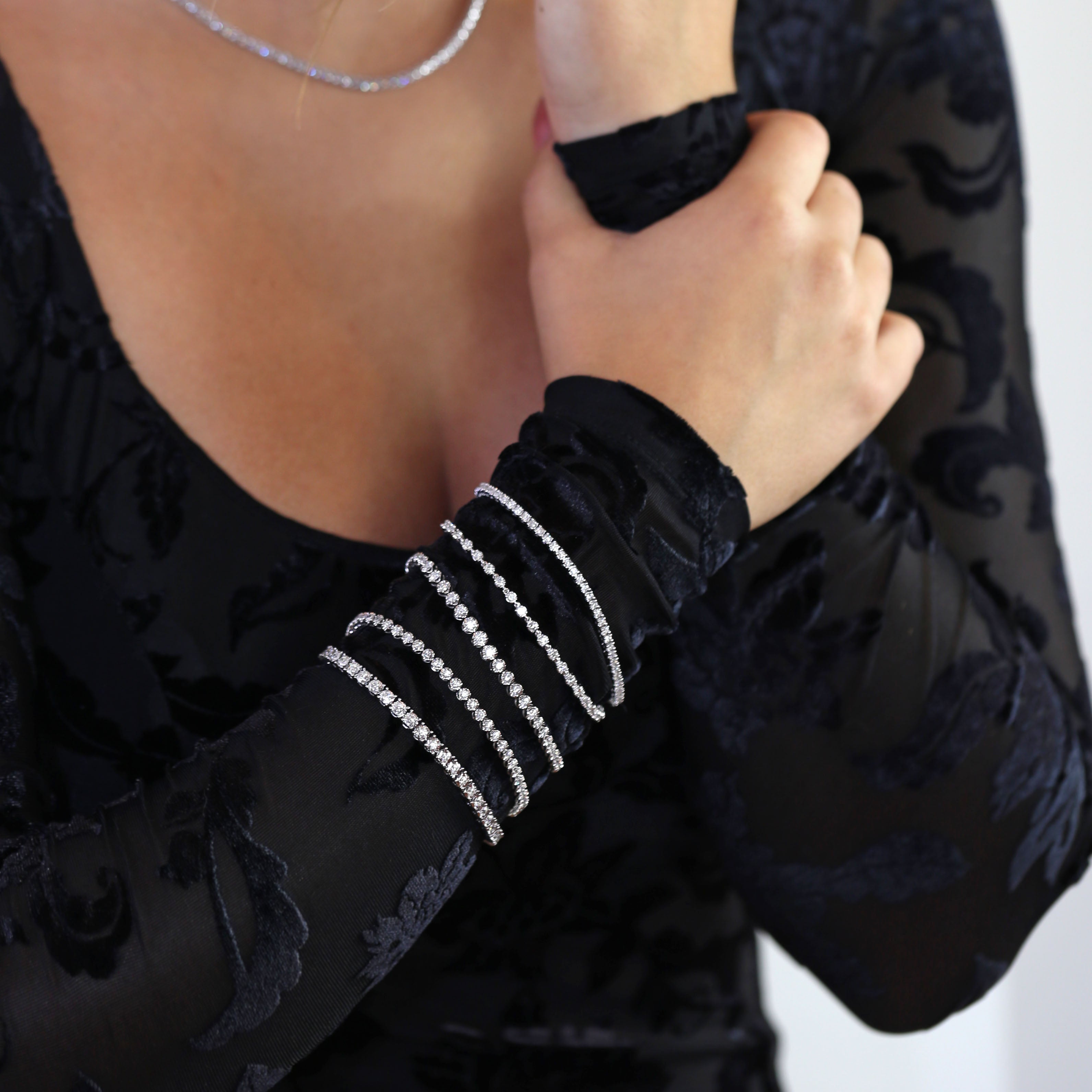 stackable tennis bracelets on black sleeve