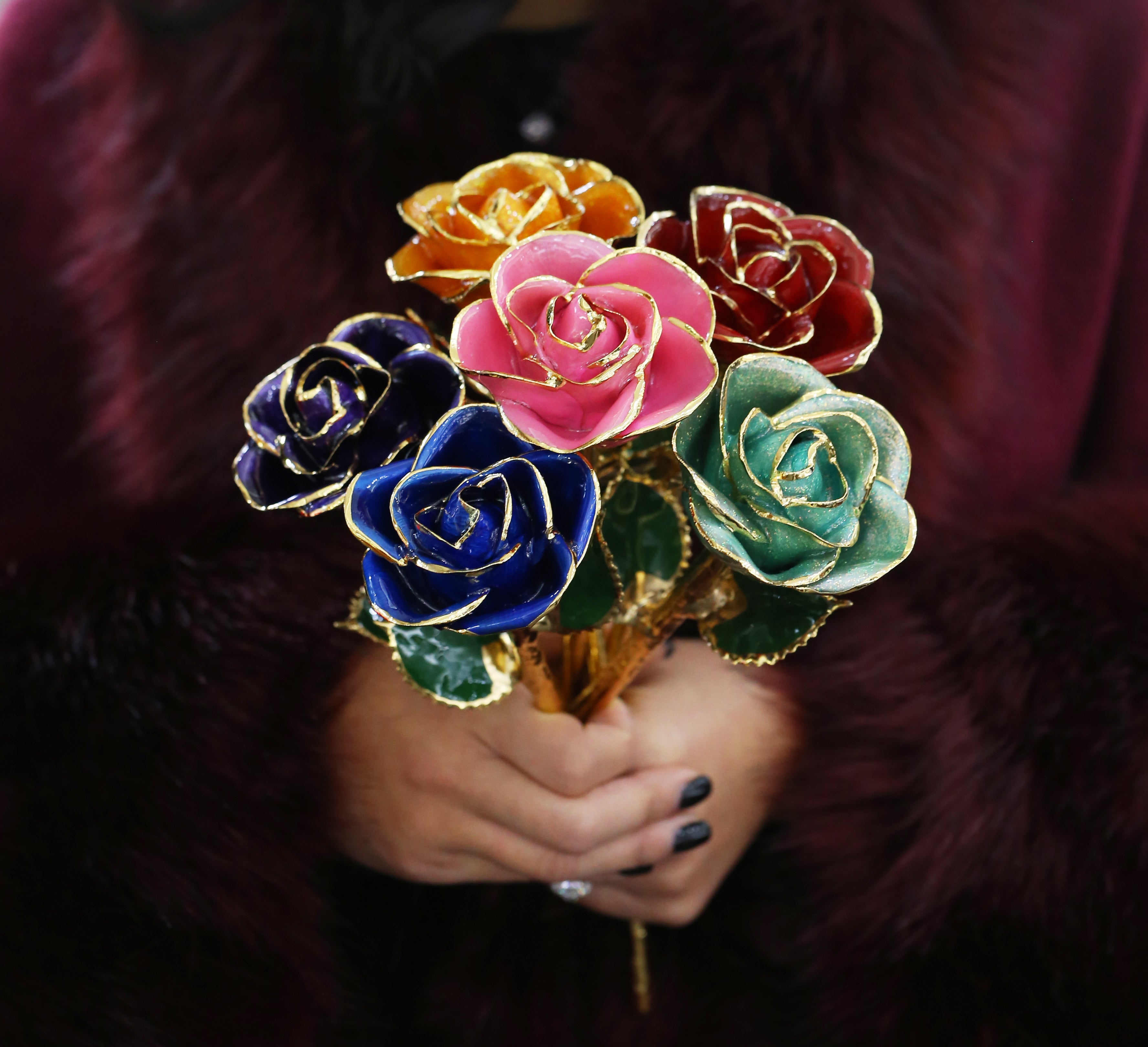 A bouquet of our 24kt gold dipped roses in a woman's hand.