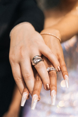 A woman's hand over another woman's showing off both of their rings.