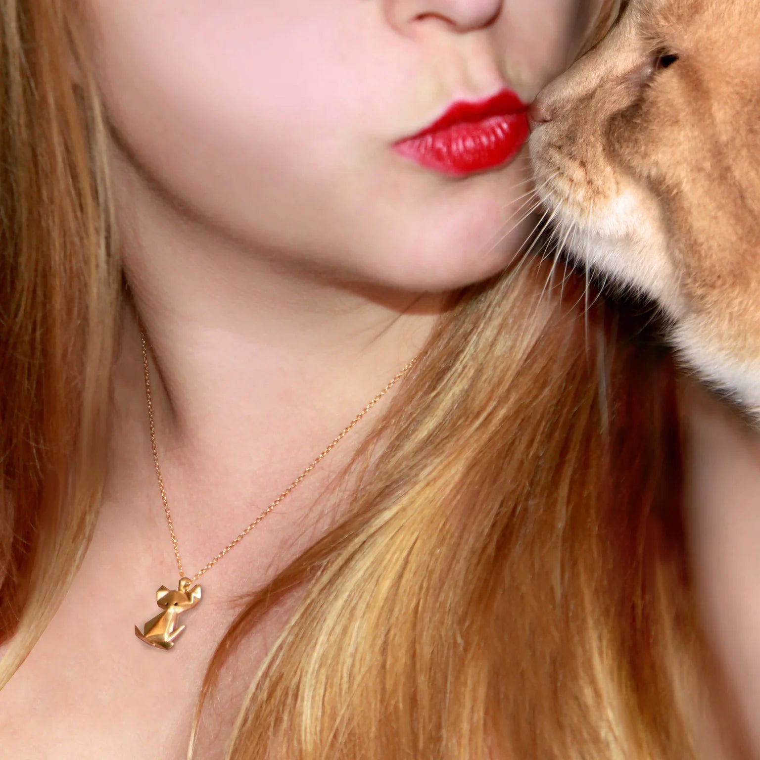 A woman wearing an Origami Cat Diamond Necklace pictured with an orange cat.