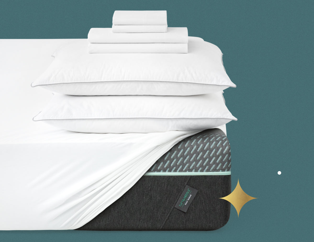 Stacked on top of a Tuft & Needle mint mattress is a mattress protector, two down alternative pillows, folded sheets and folded pillowcases. Picture has a bluish green background with gold stars.