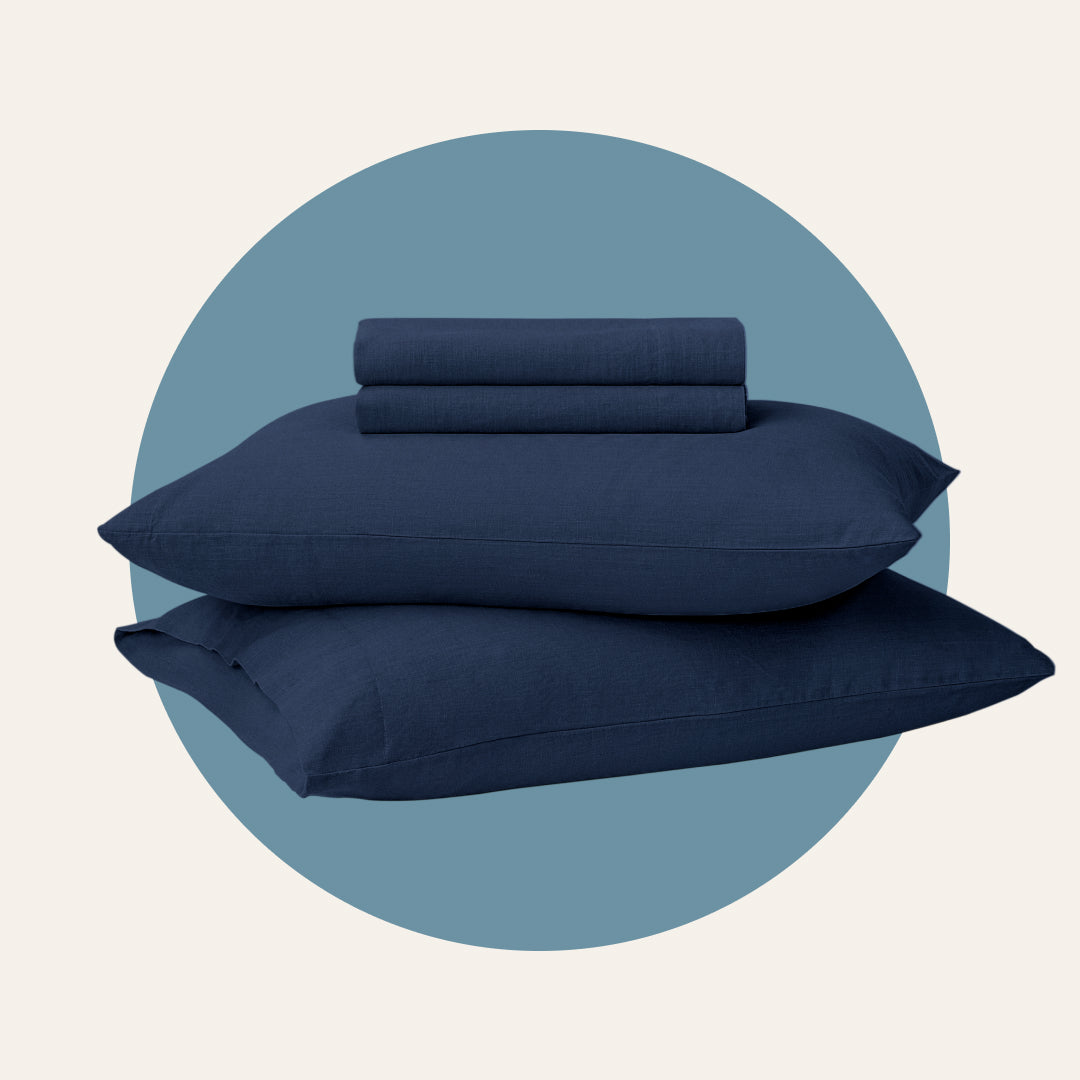 Picture of two pillows stacked on each other with blue sheets folded on top