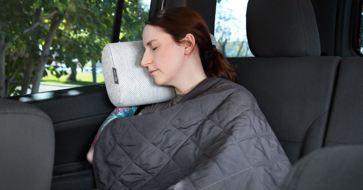 Woman sleeping in a car on the T&N Anywhere Travel Pillow