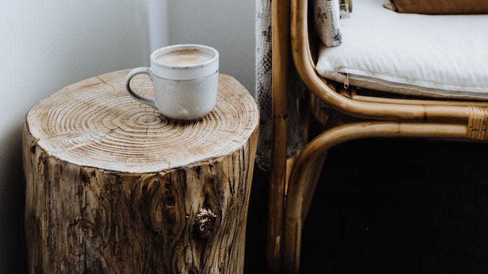 Bedside table made of a log with a coffee mug placed on top