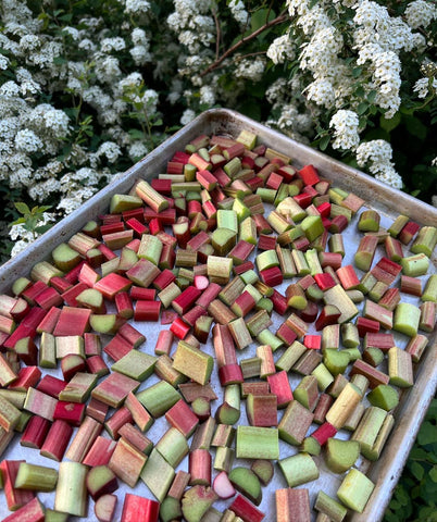 a baking tray full of chopped rhubarb being presented beside some white flowers