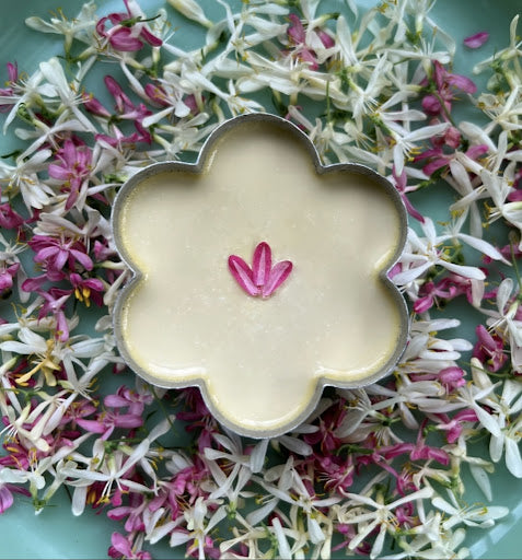 a panna cotta style dessert in a flower-shaped tin, plated amoungst wild flowers. 