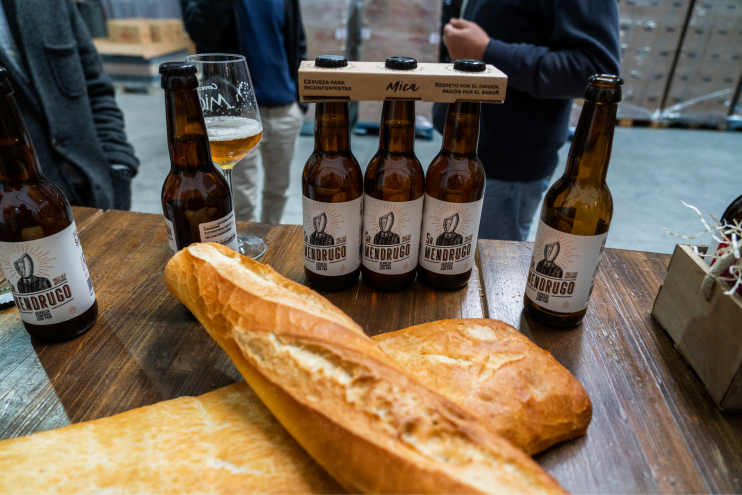 Mesa con botellines de la cerveza señor Mendrugo y dos barras de pan.