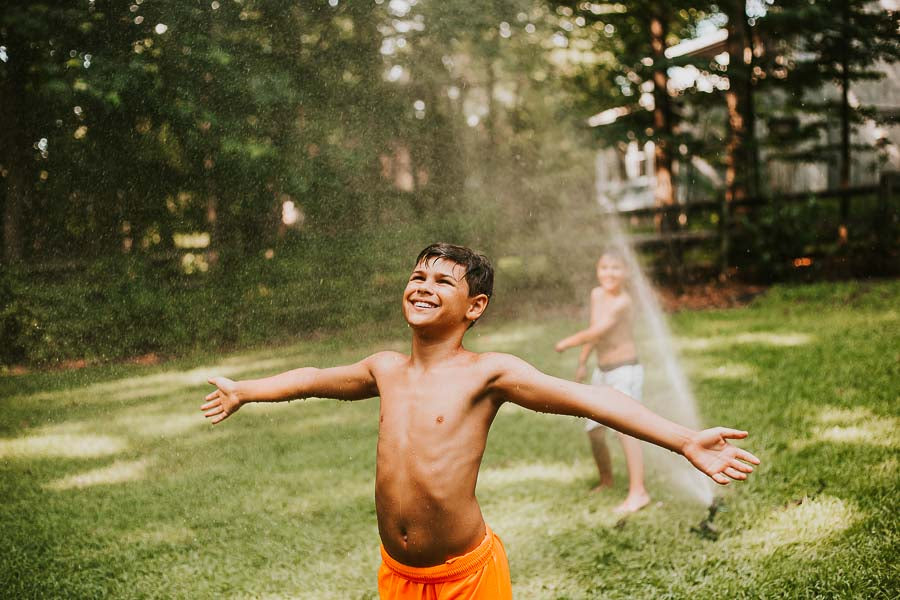 boy playing in sprinkler