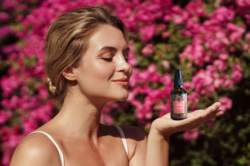 woman-with-smooth-skin-and-natural-makeup holding a product bottle