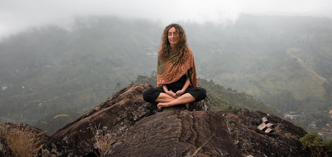 Woman meditating on top of mountain