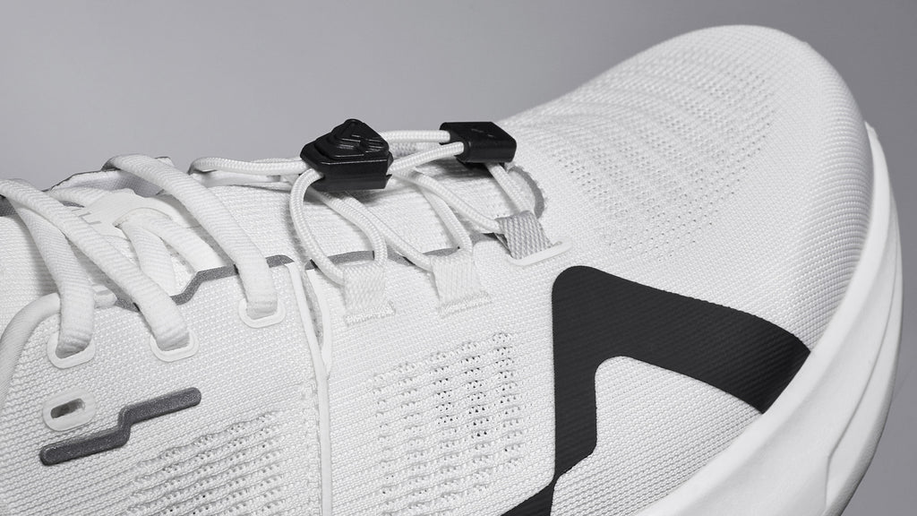 A close-up of a white running shoe showcases its laces, textured fabric, and design elements.
