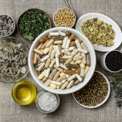 a bowl of supplements surrounded by various natural ingredients