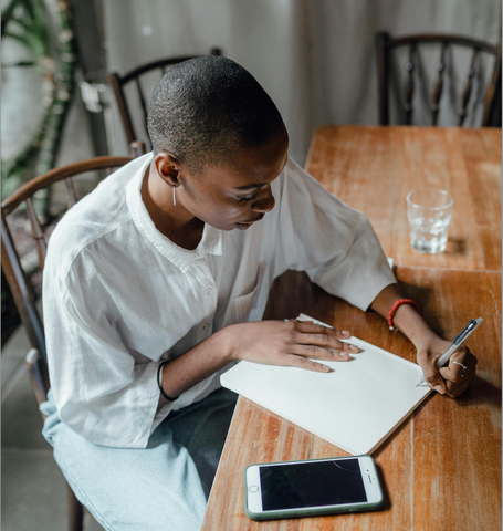 girl sitting at design writing on a paper