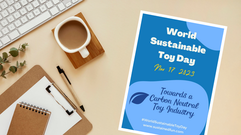 A stock photo looking down on a desk with a cup of coffee, a keyboard and a clipboard, with a poster advertising World Sustainable Toy day Nov 17 2023. Towards a Carbon Neutral Toy Industry