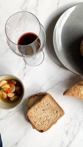 Garlic confit alongside a navy linen napkin, bread and wine.