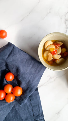 Garlic confit alongside navy linen napkin and cherry tomatoes