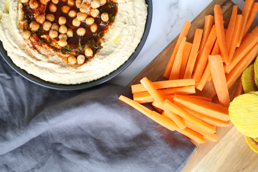 Hummus dip with carrot sticks, crackers and charcoal grey linen napkin