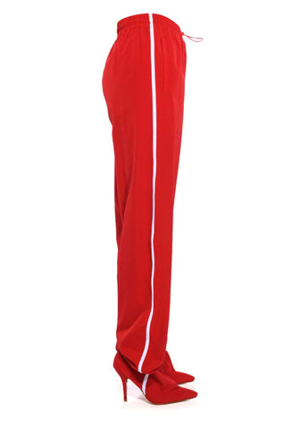 side view of slouchy bright red track pants with pointed toe stiletto heels attached